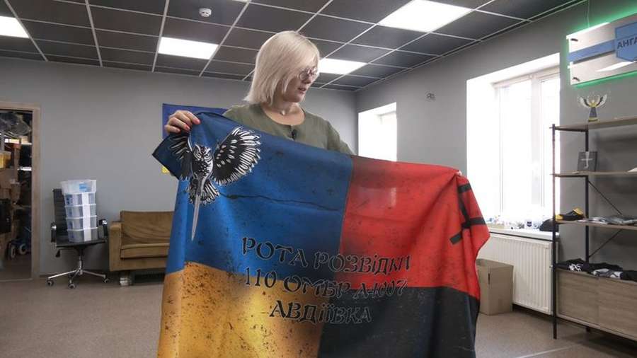 Юлія Савчук показує прапор роти розвідників 110-ої бригади з Авдіївки