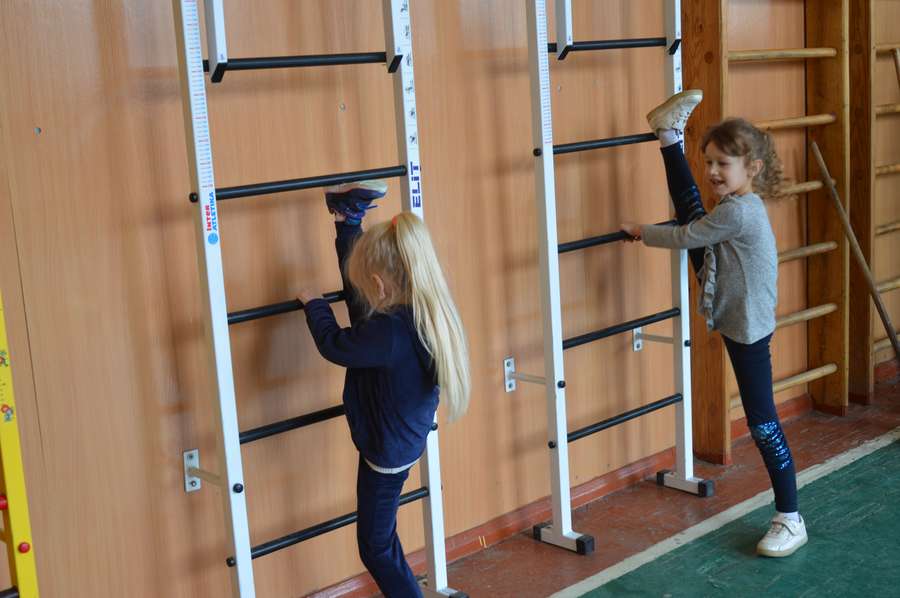 В спортзалі діти займаються вправами на нових «шведських стінках»